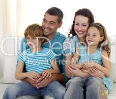 Family sitting on sofa watching television