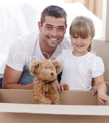 Father and daughter with a teddy bear moving home