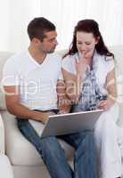 Portrait of couple buying online with a credit card on sofa