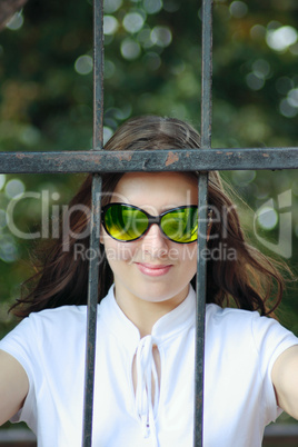 The young woman in sun glasses behind an iron protection