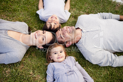 Family lying in a park with heads together