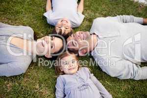 Family lying in a park with heads together