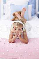 Little girl lying in bed listening to the music