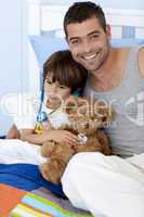 Father and sick son playing doctors in bed