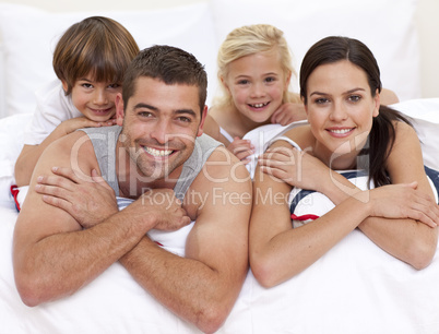 Happy family playing in parent's bed
