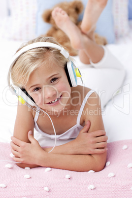 Portrait of little girl lying in bed listening to the music