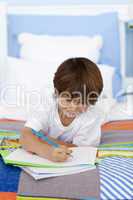 Little boy drawing in bed
