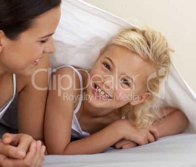Mother and daughter playing under the bedsheets