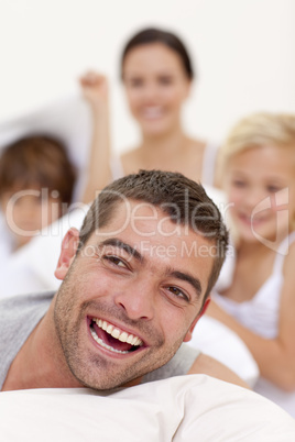 Portrait of father playing with family in bed