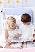 Brother and sister reading a book in bedroom