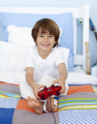 Boy playing videogames sitting in his bed