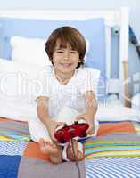 Boy playing videogames sitting in his bed