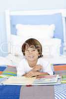 Smiling little boy reading in bed