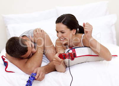 Young couple playing videogames in bed