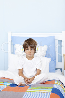Sad little boy listening to music in bed