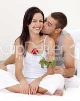 Man kissing a woman and holding a rose