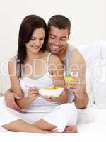 Couple having nutritive breakfast sitting in bed