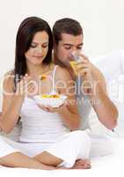 Couple eating fruit and drinking orange juice in bed