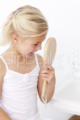 Little girl looking in a small mirror