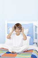 Little boy listening to music in his bed