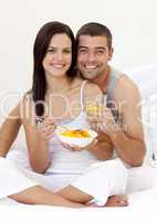 Couple eating fruit and orange juice in bed
