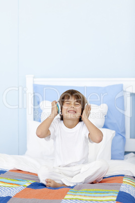 Little boy listening to music on headphones in his bed