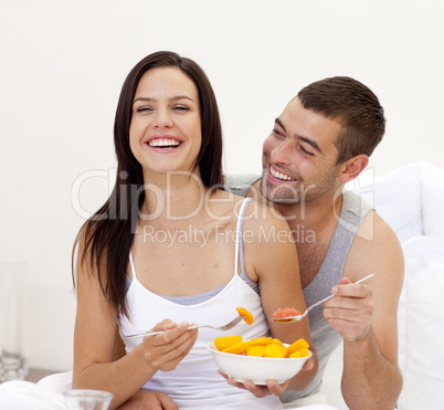 Smiling couple having nutritive breakfast in bed