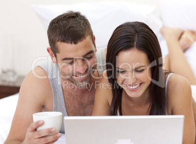 Couple in bed having fun with a laptop