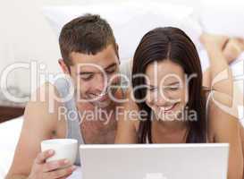Couple in bed having fun with a laptop