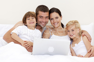 Portrait of family using a laptop in bed