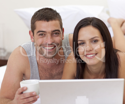 Portrait of couple in bed using a laptop