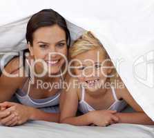 Mother and daughter under the bedsheets
