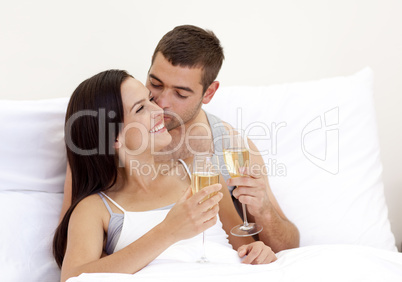 Lovers drinking champagne in bed