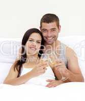Couple tusting with champagne in bed