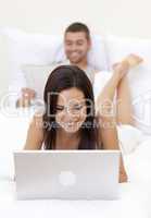 Woman using a laptop and man reading a newspaper
