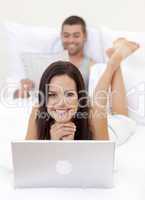 Beautiful woman using a laptop and man reading a newspaper