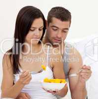 Young couple eating fruit in bed