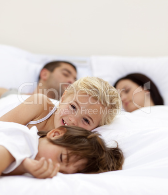 Little girl smiling wile her parents and brother sleep