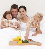 Happy family having breakfast in bedroom