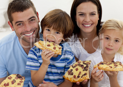 Portrait of family eating pizza in living-room