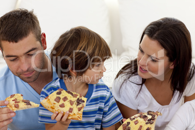 Parents and son eating pizza in living-room