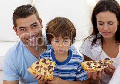 Prents and boy eating pizza in living-room