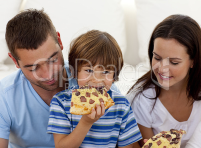 Happy boy eating pizza with ihs parents