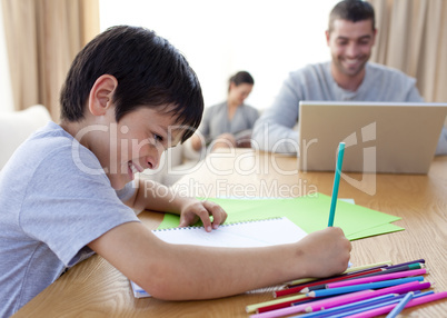 Boy drawing and parents working at home
