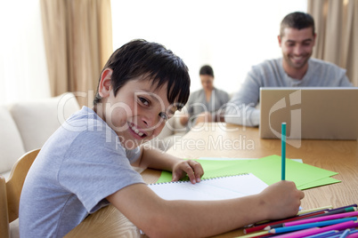 Boy painting and father using a laptop and mother reading
