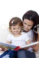 Mother and daughter reading a book on sofa