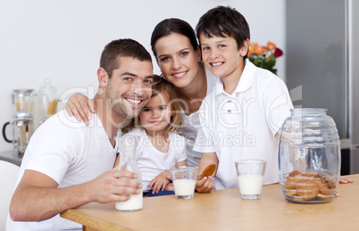 Happy family eating biscuits and drinking milk