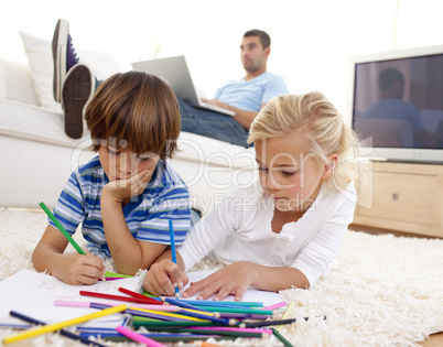 Children painting in living-room and father using a laptop