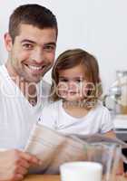 Smiling father reading a newspaper with his daughter