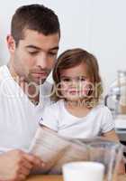 Father reading a newspaper with his daughter
